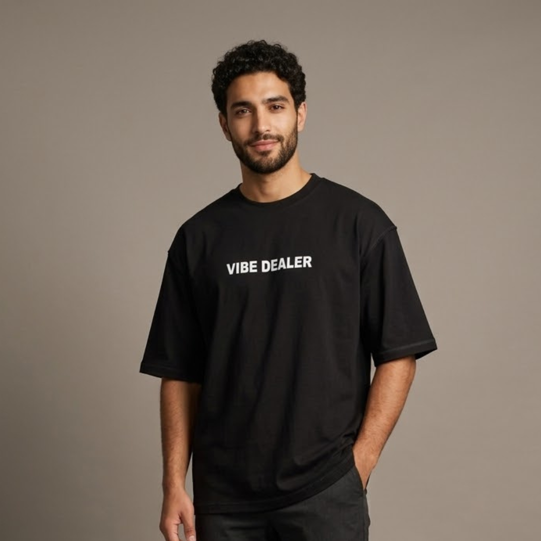 تيشيرت أسود مقاس كبير من شوب فايف بكتابة VIBE DEALER بيضاء على الصدر، يرتديه شخص